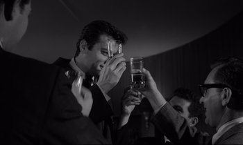 Movie still from “Sweet Smell of Success” (1957), directed by Alexander Mackendrick – A man holding a glass in front of another man's face; Medium shot, Low angle