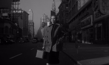 Movie still from “Sweet Smell of Success” (1957), directed by Alexander Mackendrick – A black and white photo of a woman with a briefcase; Medium shot, Low angle