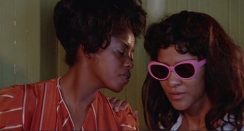 Movie still from “Sweet Sweetback's Baadasssss Song” (1971), directed by Melvin Van Peebles – Two women wearing pink sunglasses and one of the women has her hand on her shoulder; Close Up shot, Low angle
