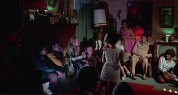 Movie still from “Sweet Sweetback's Baadasssss Song” (1971), directed by Melvin Van Peebles – A group of people sitting in a living room; Wide shot, High angle