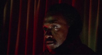 Movie still from “Sweet Sweetback's Baadasssss Song” (1971), directed by Melvin Van Peebles – A man with a beard is looking at the camera; Close Up shot, Low angle