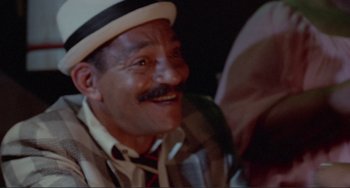 Movie still from “Sweet Sweetback's Baadasssss Song” (1971), directed by Melvin Van Peebles – An older man wearing a hat and a tie; Close Up shot, High angle