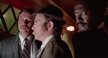Movie still from “Sweet Sweetback's Baadasssss Song” (1971), directed by Melvin Van Peebles – A group of men standing next to each other in a room; Close Up shot, Low angle