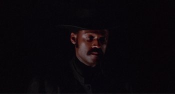 Movie still from “Sweet Sweetback's Baadasssss Song” (1971), directed by Melvin Van Peebles – A man in a cowboy hat is looking at the camera; Close Up shot, Low angle