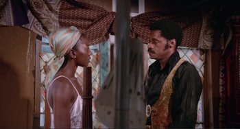 Movie still from “Sweet Sweetback's Baadasssss Song” (1971), directed by Melvin Van Peebles – A man and a woman standing next to each other in front of an awning; Medium shot, Low angle