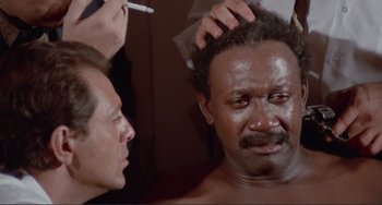 Movie still from “Sweet Sweetback's Baadasssss Song” (1971), directed by Melvin Van Peebles – A man getting his head shaved by a barber; Close Up shot, High angle