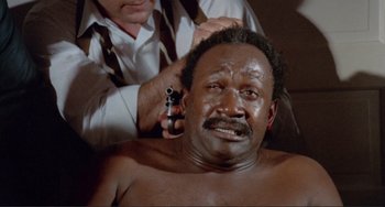 Movie still from “Sweet Sweetback's Baadasssss Song” (1971), directed by Melvin Van Peebles – A man is getting his head shaved by another man; Close Up shot, High angle