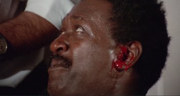 Movie still from “Sweet Sweetback's Baadasssss Song” (1971), directed by Melvin Van Peebles – A man with an ear tag on his left ear; Close Up shot, Low angle
