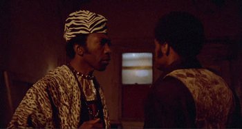 Movie still from “Sweet Sweetback's Baadasssss Song” (1971), directed by Melvin Van Peebles – Two men are standing in a room and one of them is wearing a zebra print hat; Close Up shot, Low angle