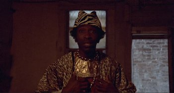Movie still from “Sweet Sweetback's Baadasssss Song” (1971), directed by Melvin Van Peebles – A man in a leopard print outfit holding a gold chain; Close Up shot, Low angle