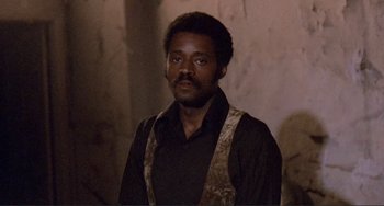 Movie still from “Sweet Sweetback's Baadasssss Song” (1971), directed by Melvin Van Peebles – A man in a black shirt and a brown vest; Close Up shot, Low angle
