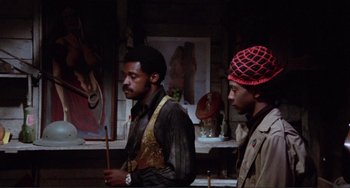 Movie still from “Sweet Sweetback's Baadasssss Song” (1971), directed by Melvin Van Peebles – A couple of men standing next to each other in a room; Medium shot, Low angle