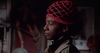 Movie still from “Sweet Sweetback's Baadasssss Song” (1971), directed by Melvin Van Peebles – A young man wearing a crocheted hat looking to his left; Close Up shot, Low angle