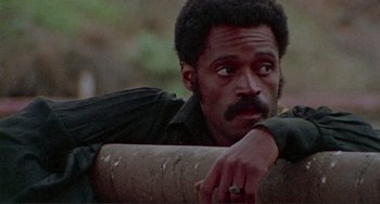 Movie still from “Sweet Sweetback's Baadasssss Song” (1971), directed by Melvin Van Peebles – A person leaning on a wall; Close Up shot, Low angle