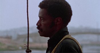 Movie still from “Sweet Sweetback's Baadasssss Song” (1971), directed by Melvin Van Peebles – A man with a beard is looking to the side; Close Up shot, Over the shoulder angle