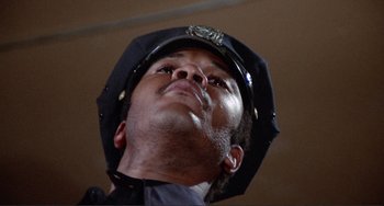 Movie still from “Sweet Sweetback's Baadasssss Song” (1971), directed by Melvin Van Peebles – A man in a police uniform looking up at the sky; Close Up shot, Low angle