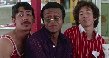 Movie still from “Sweet Sweetback's Baadasssss Song” (1971), directed by Melvin Van Peebles – A group of men standing next to each other; Medium shot, Low angle