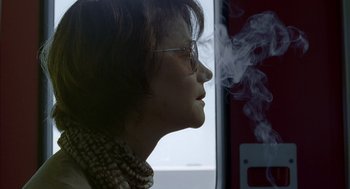 Movie still from “Swimming Pool” (2003), directed by François Ozon – A woman wearing glasses is looking out a window; Close Up shot, Low angle