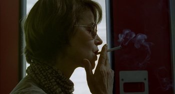 Movie still from “Swimming Pool” (2003), directed by François Ozon – A woman smoking a cigarette in front of a window; Close Up shot, Low angle