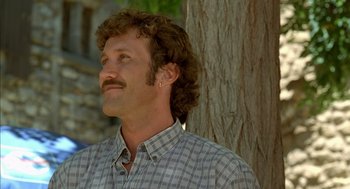 Movie still from “Swimming Pool” (2003), directed by François Ozon – A person wearing a plaid shirt near a tree; Close Up shot, Low angle