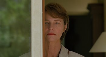 Movie still from “Swimming Pool” (2003), directed by François Ozon – A person standing in front of a window; Close Up shot, Low angle