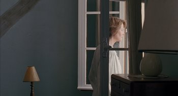 Movie still from “Swimming Pool” (2003), directed by François Ozon – A woman looking out of a window at a room; Medium shot, Over the shoulder angle
