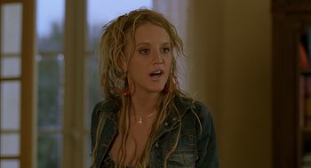 Movie still from “Swimming Pool” (2003), directed by François Ozon – A young woman with dreads is standing in a room; Close Up shot, Over the shoulder angle