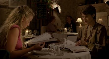 Movie still from “Swimming Pool” (2003), directed by François Ozon – Two people are sitting at a table in front of a menu; Medium shot, Over the shoulder angle