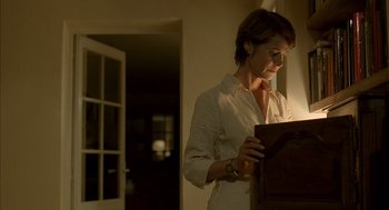 Movie still from “Swimming Pool” (2003), directed by François Ozon – A woman standing in a room holding a book; Medium shot, Low angle
