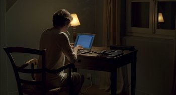 Movie still from “Swimming Pool” (2003), directed by François Ozon – A woman sitting at a desk using a laptop computer; Medium shot, High angle