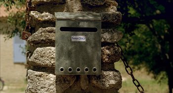 Movie still from “Swimming Pool” (2003), directed by François Ozon – An old mailbox is attached to the side of a stone wall; Extreme Close Up shot, High angle