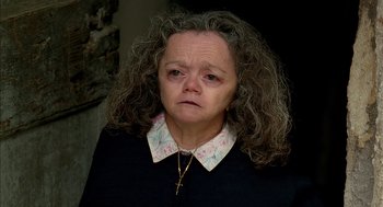 Movie still from “Swimming Pool” (2003), directed by François Ozon – An older woman wearing a black shirt and a cross necklace; Close Up shot, High angle