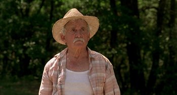 Movie still from “Swimming Pool” (2003), directed by François Ozon – An older man wearing a straw hat and a plaid shirt; Close Up shot, Low angle