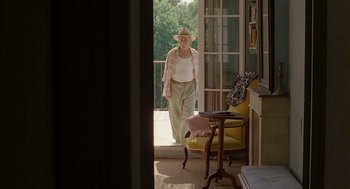 Movie still from “Swimming Pool” (2003), directed by François Ozon – An older woman walking out of a door; Wide shot, Low angle
