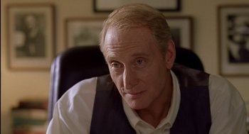 Movie still from “Swimming Pool” (2003), directed by François Ozon – An older man sitting in a chair looking at the camera; Close Up shot, Over the shoulder angle