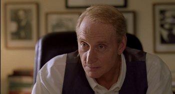 Movie still from “Swimming Pool” (2003), directed by François Ozon – An older man sitting in a chair looking at the camera; Close Up shot, Over the shoulder angle