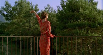 Movie still from “Swimming Pool” (2003), directed by François Ozon – A woman standing on a balcony with her arms outstretched; Wide shot, Low angle