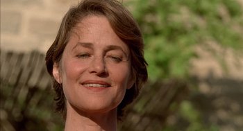 Movie still from “Swimming Pool” (2003), directed by François Ozon – A person smiling with trees in the background; Close Up shot, Low angle