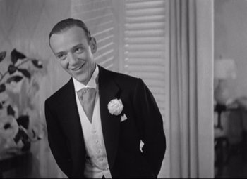 Movie still from “Swing Time” (1936), directed by George Stevens – An old photo of a man in a suit and tie; Medium shot, Low angle