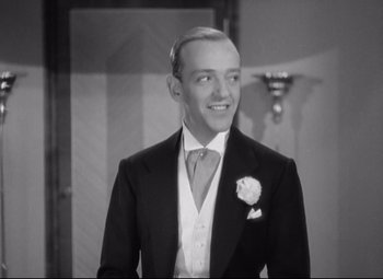 Movie still from “Swing Time” (1936), directed by George Stevens – A black and white photo of a man in a suit and tie; Medium shot, Low angle