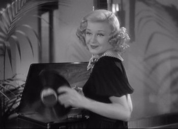 Movie still from “Swing Time” (1936), directed by George Stevens – A black - and - white photo of a woman holding a record player; Medium shot, High angle