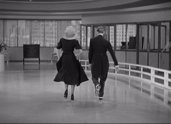 Movie still from “Swing Time” (1936), directed by George Stevens – A man and a woman are walking in a building; Wide shot, High angle