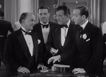 Movie still from “Swing Time” (1936), directed by George Stevens – A group of men in tuxedos standing around a table; Medium shot, High angle