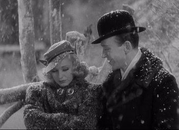 Movie still from “Swing Time” (1936), directed by George Stevens – A man and a woman are sitting in the snow together; Medium shot, High angle