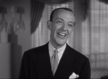 Movie still from “Swing Time” (1936), directed by George Stevens – A man wearing a suit and tie smiling for the camera; Close Up shot, Low angle