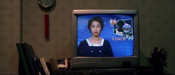 Movie still from “Sympathy for Lady Vengeance” (2005) – A woman is on a television screen in front of a clock; Close Up shot, Over the shoulder angle