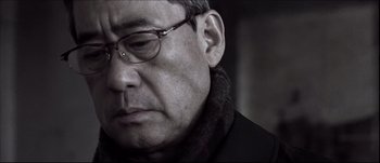 Movie still from “Sympathy for Lady Vengeance” (2005) – An older man with glasses is looking at the camera; Close Up shot, Low angle