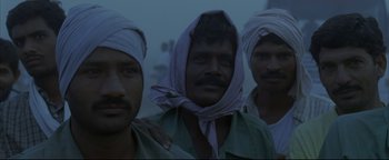 Movie still from “Syriana” (2005), directed by Stephen Gaghan – A group of men standing next to each other; Medium shot, Low angle