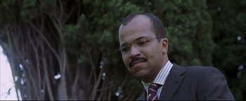 Movie still from “Syriana” (2005), directed by Stephen Gaghan – A person wearing a suit and tie; Close Up shot, Low angle