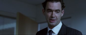 Movie still from “Syriana” (2005), directed by Stephen Gaghan – A person wearing a suit and tie; Close Up shot, Over the shoulder angle